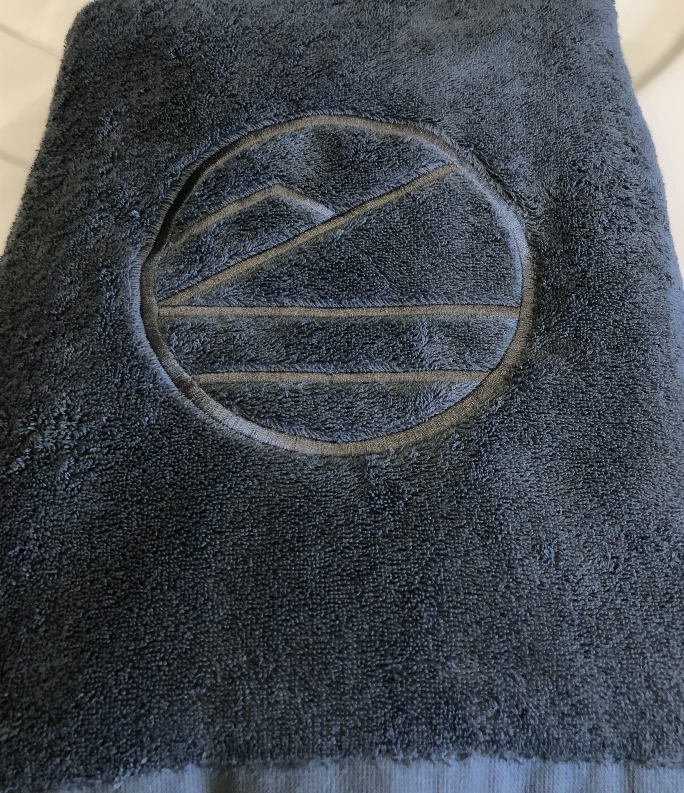 Luksuriøst badehåndkle i bomull med høy absorberingsevne og brodert logo. Perfekt til spa, badstue og hverdagsbruk – komfort og kvalitet i ett.